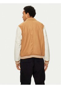 Giacca varsity marrone e bianca con maniche a contrasto, polsini e orlo a coste. Tessuto morbido con una superficie liscia, con righe sul colletto.