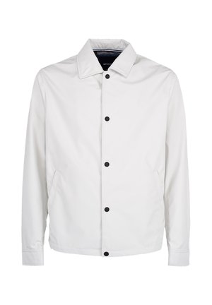 Biała kurtka z długim rękawem z ostrym kołnierzem, czarne zatrzaski z przodu i boczne kieszenie na jednolitym tle.