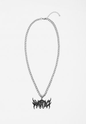 Collier chaîne en argent avec fermoir ajustable et pendentif en métal noir présentant un texte stylisé aux bords tranchants.
