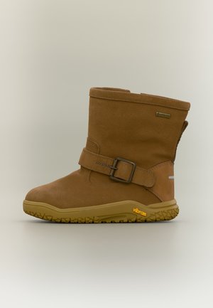 Brun ruskind ankelstøvle med gummisål, justerbar rem med metalspænde, Gore-Tex mærkat og Vibram branding på sålen.