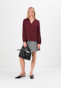Burgunder v-halsbluse med lange ærmer, grå høj Talje nederdel, sort tekstureret håndtaske og sorte slingback sko med spidse tås.