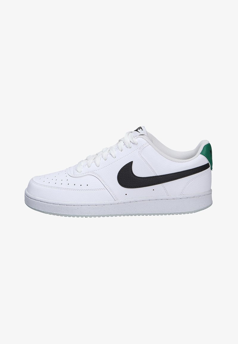 Zapatillas deportivas blancas con parte superior de cuero texturizado, logo Swoosh negro, acentos grises y un tirador verde en el talón. Suela de goma para mejor agarre.