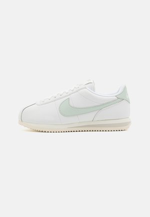 Zapatos de cuero blancos con acentos en verde claro. Punta redonda, diseño de cordones y suela texturizada con un patrón en zigzag. Estilo minimalista.