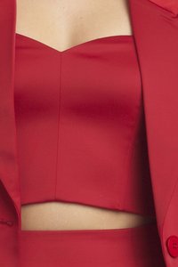 Crvena bralette bez naramenica napravljena od glatkog materijala, s prilagođenim dizajnom i detaljem šava, uparen s odgovarajućim crvenim sakoom.