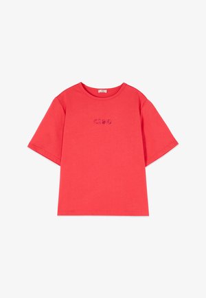 Camiseta roja de manga corta con texto "ciao" hecho de pequeñas cuentas decorativas centradas en el pecho, cuello redondo.