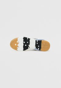 Suola della scarpa con un design a più motivi in bianco, nero e marrone. Presenta motivi esagonali e bulbi di trazione arrotondati per una migliore aderenza.