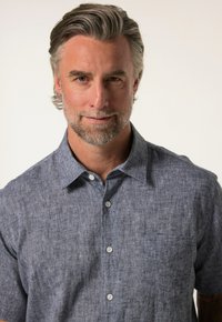 Lyhythihainen kauluspaita tummansinisessä teksturoidussa kankaassa, jossa on tasku ja valkoiset napit. H subtle kuvio lisää visuaalista kiinnostavuutta.