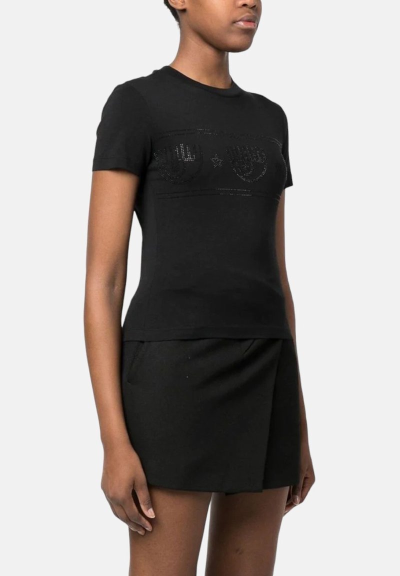 Schwarzes, eng anliegendes T-Shirt mit kurzen Ärmeln, das ein strukturiertes Vorderdesign und einen Rundhalsausschnitt aufweist, kombiniert mit einem hochgeschnittenen schwarzen Rock.