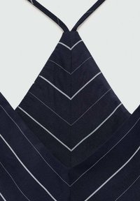 Temno modra tkanina z sivimi diagonalnimi črtami, ki oblikujejo ševronski vzorec. Ima tanke naramnice in V-izrez.