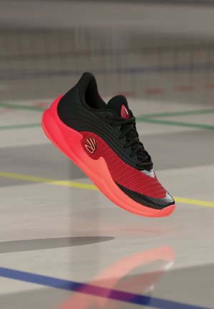 Rood en zwart sportschoen zwevend boven een gymzaalvloer met kleurrijke lijnmarkeringen en een reflecterend oppervlak.