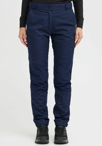Navy blue outdoor pants made of textured fabric, featuring a zippered pocket, reinforced knees, and adjustable cuffs, paired with black footwear.