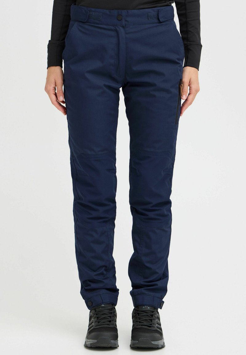 Navy blue outdoor pants made of textured fabric, featuring a zippered pocket, reinforced knees, and adjustable cuffs, paired with black footwear.