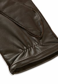 Gant en cuir marron avec une surface texturée, un détail de poignet froncé et des coutures renforcées le long des bords pour plus de durabilité.