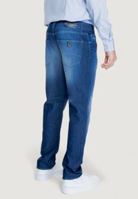 Jeans in denim di colore blu scuro con un effetto sfumato sbiadito, taglio dritto, design a cinque tasche e un patch con il logo sulla cintura.
