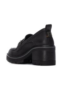 Zapatos de tacón de cuero negro con un tacón ancho, textura suave y detalles en acero plateado. Presentan una parte trasera elevada con un acento de "R".