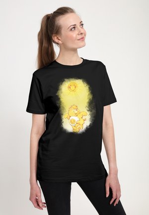 Sort bomulds T-shirt med en central grafik af en gul tegneseriekat med en sol, omkranset af et lysgult skær.