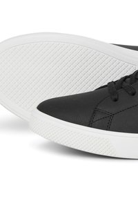 Sorte lædersneakers med en glat overflade, der har en hvid gummisål, flade snørebånd og en diamantmønsteret sål for bedre greb.