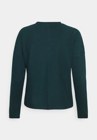 Dunkelgrünes, strukturiertes Langarmoberteil mit rundem Halsausschnitt, das eine vertikale Naht auf der Mitte des Rückens und einen leicht oversized Schnitt aufweist.