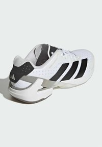 Białe buty sportowe z przewiewną siateczką, czarnym wzorem w trzy paski oraz szarym akcentem na pięcie i śródstopiu. Lekka konstrukcja.