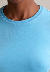 Light blue cotton t-shirt with a crew neck and short sleeves. Smooth texture, well-finished stitching along the neckline and sleeves.