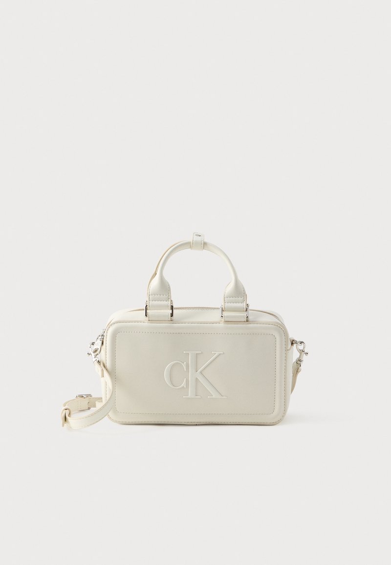 Biała skórzana torebka o prostokątnym kształcie, z rączkami u góry, odpinanym paskiem, tłoczonym logo „CK” oraz subtelnymi detalami szwów.