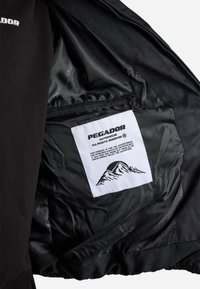 Černá vnější bunda s hladkou podšívkou, která má vnitřní štítek s vyobrazením hor a názvem značky "PEGADOR." Obsahuje zapínání na zip.