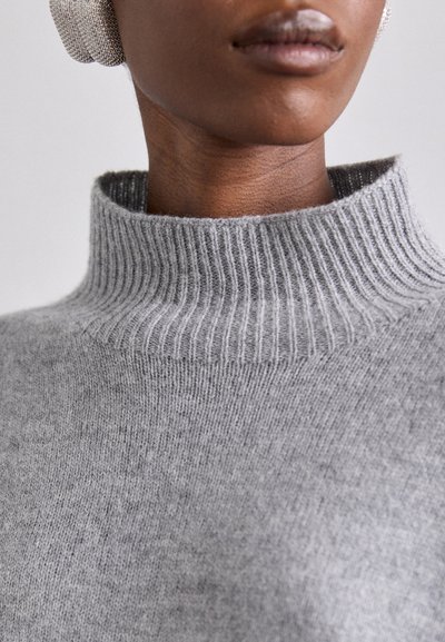 Pull gris à col montant en tricot doux avec un col côtelé et un design sans coutures, mettant en avant une texture lisse et un style minimaliste.