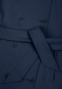 Temno modr plašč z dvorednim zapenjanjem, štirimi gumbi in pasom, ki je privezan okoli pasu, s podrobno všitki in gladko teksturo tkanine.