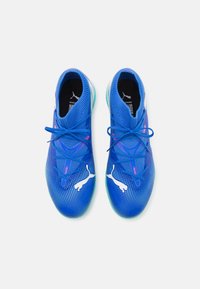 Scarpe sportive blu con una tomaia in mesh testurizzato, caratterizzate da dettagli e lacci bianchi. La suola è traslucida con un design arrotondato.