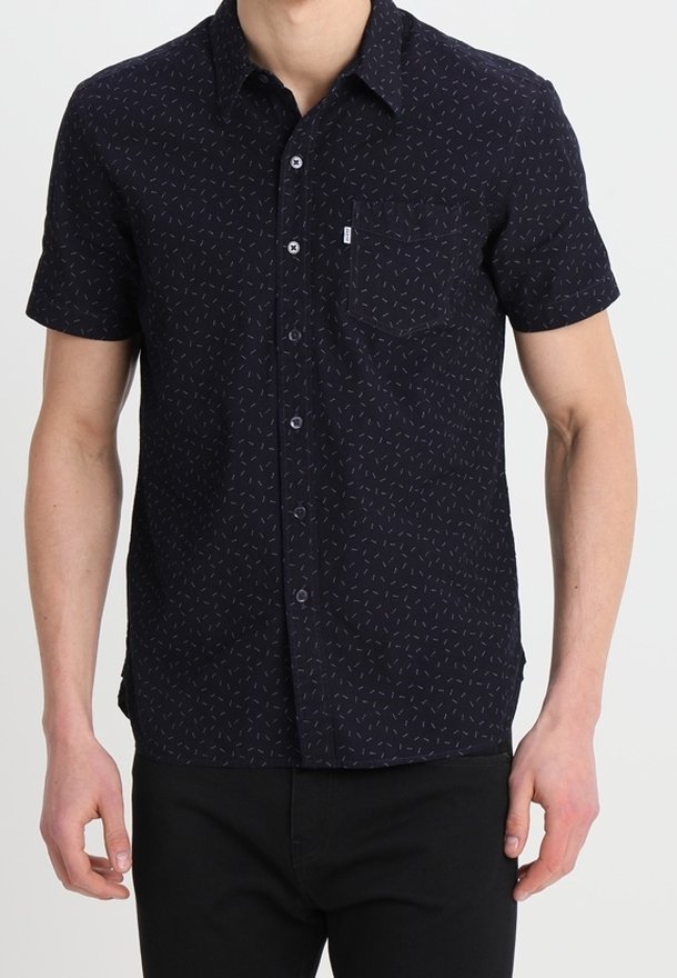 Kortärmad, mörkblå skjorta med knappar och ett subtilt geometriskt mönster, en bröstficka och en slät tygtextur.