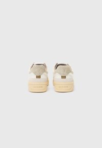 White leather shoes with beige suede accents, textured back, and a chunky light tan sole. "ALLSAINTS" embossed on the heel.