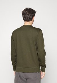Sudadera verde oliva con cuello redondo, de manga larga y puños acanalados, confeccionada en una tela suave con una textura lisa.