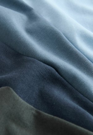 Próbki tkanin w odcieniach jasnoniebieskiego, ciemnoniebieskiego, zielonego oraz szarego, prezentujące miękką, teksturowaną powierzchnię z gładkim, tkanym wzorem.