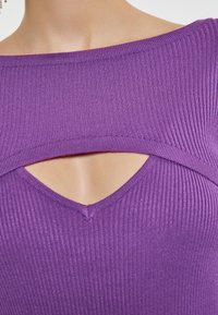 Lila gestreifter Oberteil mit weitem, schulterfreien Ausschnitt und einem kleinen Schlitz darunter. Nahtdetails verleihen dem Design Textur.