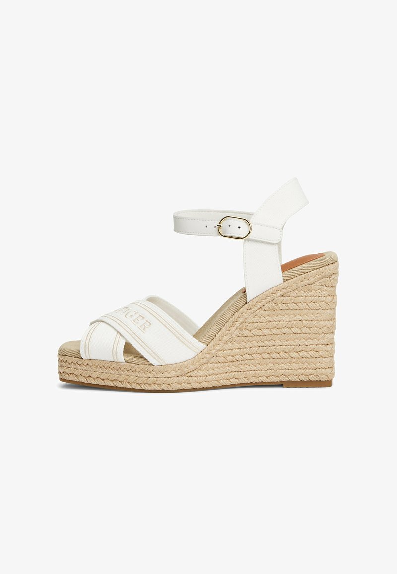 Sandales compensées blanches avec une sangle croisée en toile et une boucle à la cheville. Plateforme en espadrille texturée avec des détails en jute naturel.