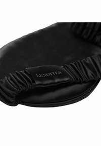 Svart satin sovmask med rynkade tygkanter och en logotypsetikett, med en slät yta och böjd form för bekväm bärning.