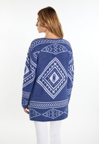 Marineblauer Strickpullover mit weißen geometrischen Mustern, im lässigen Schnitt und mit langen Ärmeln, die bis zur Mitte des Oberschenkels reichen.