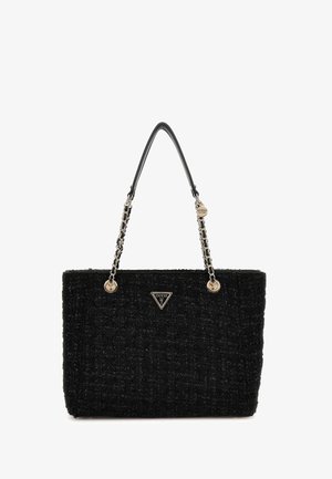 Sac fourre-tout texturé noir avec poignées en chaîne et en cuir, arborant un logo triangulaire Guess et un pendentif métallique rond sur la sangle.