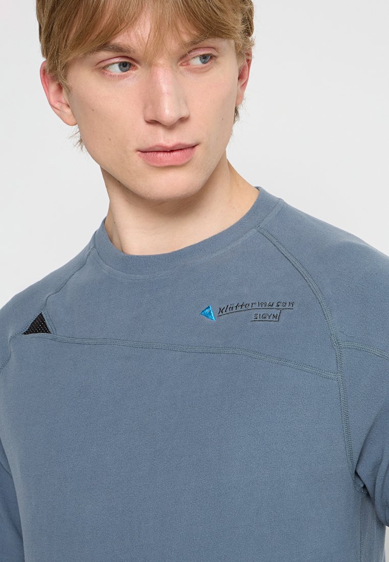 Pull-over en polaire gris avec des détails en maille noire contrastante et des accents de logo bleu. Doté d'un col rond et de manches raglan pour un meilleur confort de mouvement.