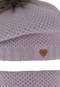 Cappello di lana viola con motivo a trama, sormontato da un pompon in pelliccia sintetica, caratterizzato da una piccola toppa di pelle marrone a forma di cuore con la scritta "LOVE".