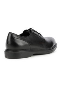 Scarpa da uomo in pelle nera con finitura liscia, punta rotonda, design con lacci e suola bassa e piatta in gomma. Presenta dettagli di cucitura discreti.