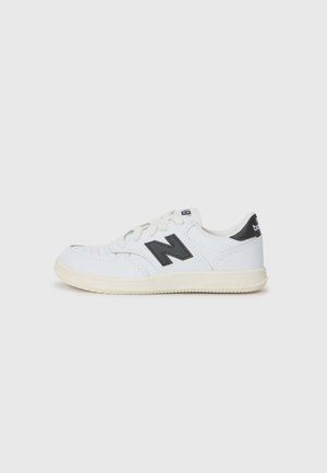 Fehér sneaker, sima bőrből készült külső résszel, fekete N logóval az oldalon, struktúrált gumitalppal és lekerekített orr kialakítással.