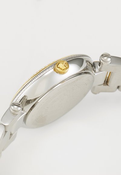 Stainless steel watch with a gold crown, textured bezel, and a detailed back. Features a silver-tone band and polished finish.