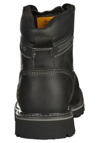 Bota de cuero negra con tobillo alto, superficie texturizada y costuras blancas en contraste. Cuenta con una suela de goma con un dibujo pronunciado.