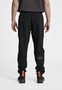 Zwarte cargo broeken met een relaxte pasvorm, met een elastische tailleband, zijzakken en een grijs "223" logo op het linkerbeen.