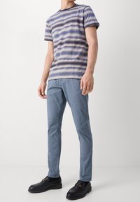 Gestreiftes Kurzarmhemd in Blau- und Neutraltönen, kombiniert mit hellblauen Slim-Fit-Hosen und schwarzen Loafers mit Schnallendetails.