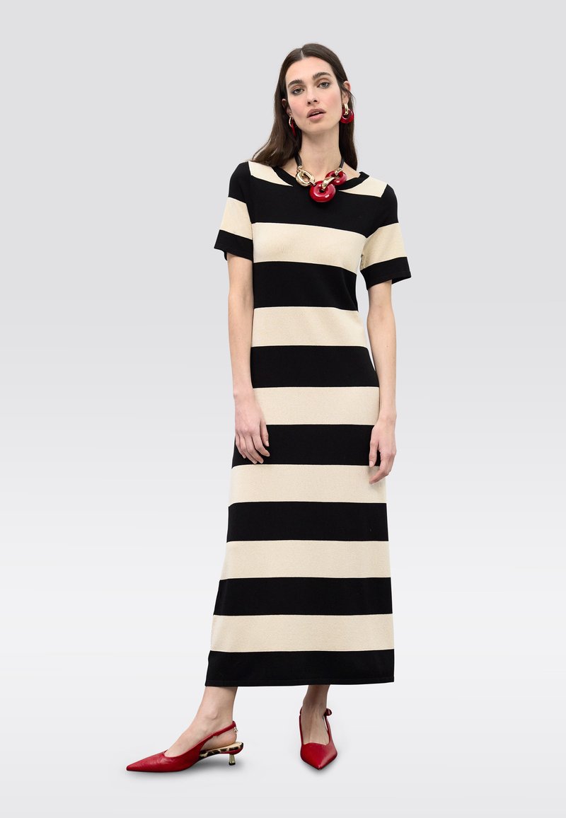 Musta-beige raidallinen mekko, jossa on lyhyet hihat ja polven mitta. Yhdistetty punaisiin slingback-korkokenkiin, joissa on kullanvärinen korostus kantapäässä.