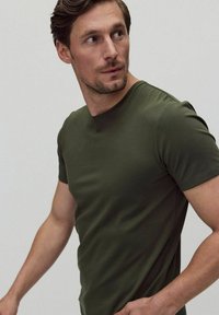 Olivegrøn kortærmet t-shirt med rund halsudskæring, glat tekstur, tætsiddende design og minimal synlig syning.