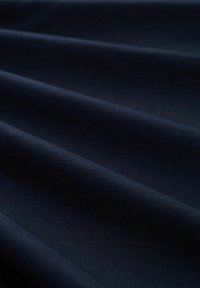 Tejido azul marino oscuro con una textura suave, que presenta sutiles ondulaciones y pliegues, resaltando su flexibilidad y peso.