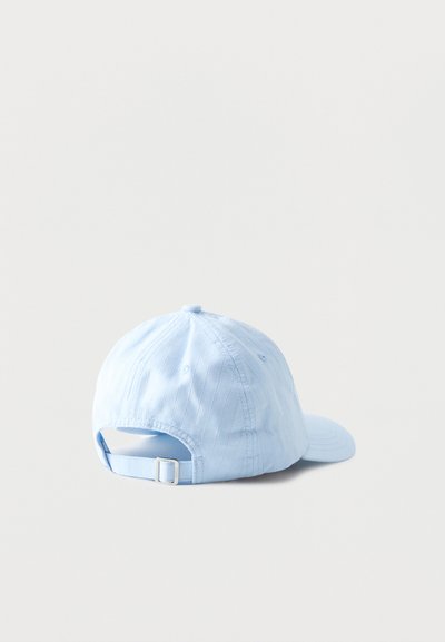 Gorra de béisbol azul claro con correa ajustable y hebilla de metal, mostrada desde atrás sobre un fondo liso y claro.